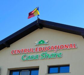 Fațada Centrului Educațional Casa Share, cu numele centrului pe clădire și steagul României pe acoperiș